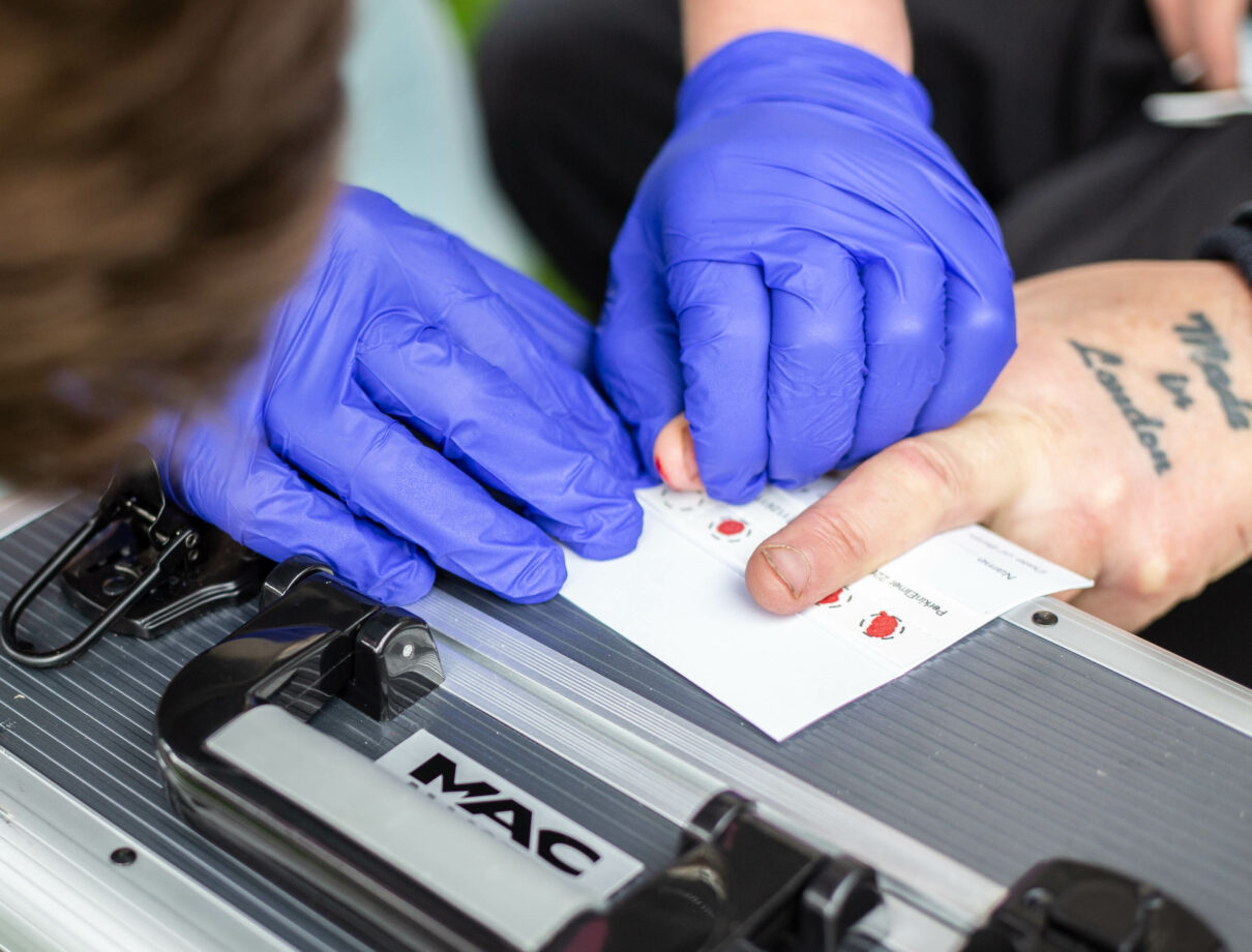 Person performs dry blood spot test for blood borne viruses